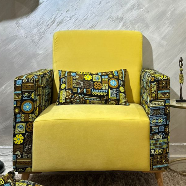 Un fauteuil jaune avec des accoudoirs décorés de motifs vibrants et un coussin assorti, sur fond mural texturé.